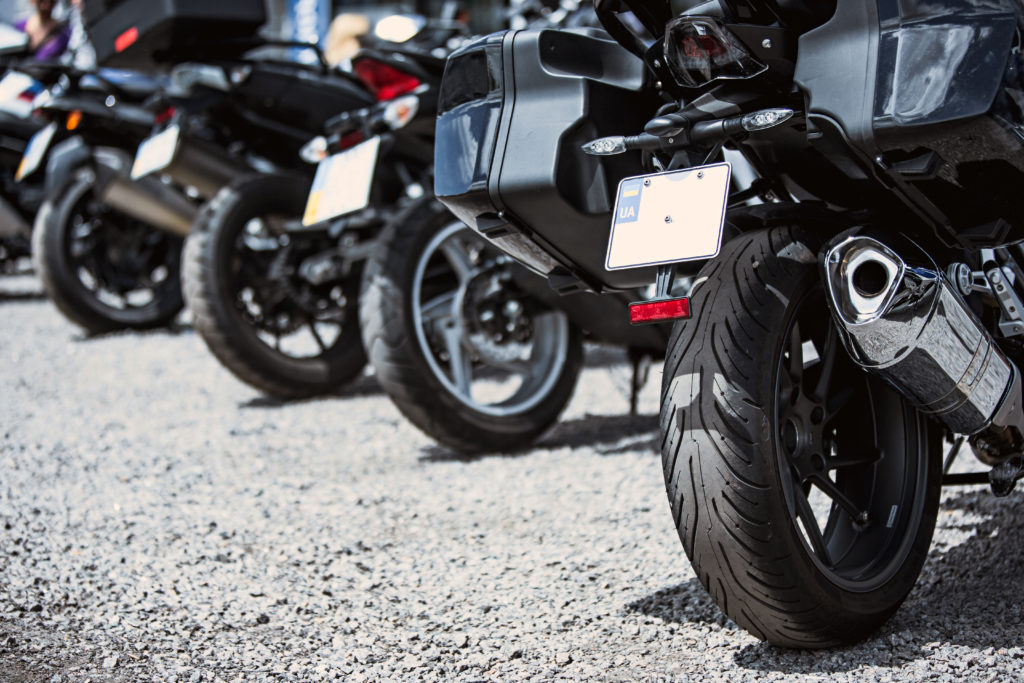 Motos estacionadas em uma fileira, imagem focada em seus pneus traseiros.
