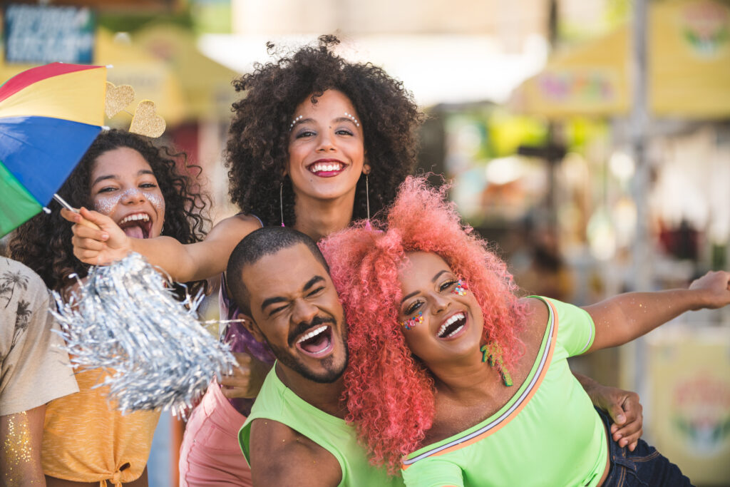 Na imagem a quatro pessoas sorrindo para uma foto, enquanto celebram e aproveitam o carnaval.