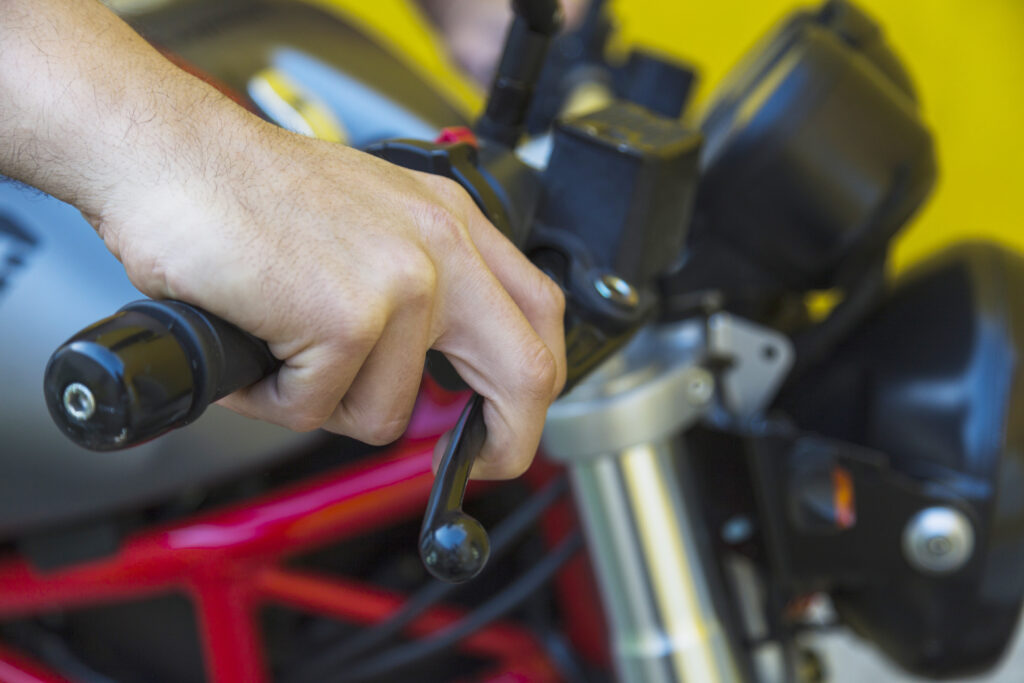 Na imagem há uma pessoa mexendo no freio da moto durante a revisão de moto.
